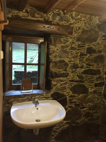 a bathroom with a sink and a stone wall at Casa de Baixo in Lousã