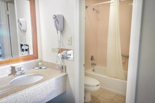 a bathroom with a sink and a toilet and a phone at University Inn & Suites in San Antonio