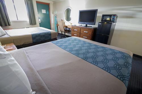 a hotel room with two beds and a flat screen tv at University Inn & Suites in San Antonio