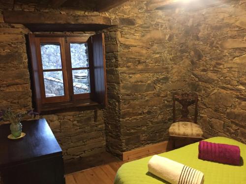 a bedroom with a bed and a stone wall at Casa de Baixo in Lousã