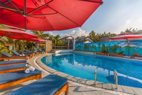 una piscina con sombrillas y sillas rojas en Palm Hills Resort, en Phu Quoc