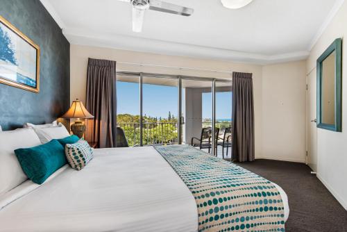 a bedroom with a large bed and a balcony at Rovera Apartments in Maroochydore