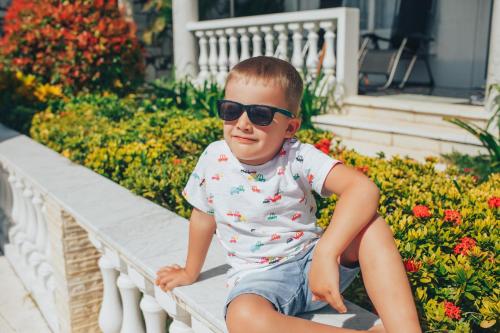 a young boy sitting on a bench wearing sunglasses at Godiva Villa Phu Quoc in Phu Quoc