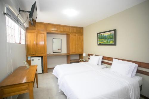 a bedroom with two beds and a desk and a tv at Hotel Acosta in Iquitos