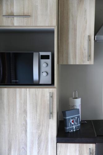 a microwave in a wooden cabinet in a kitchen at Au Moulin à Paroles in Tournai