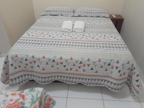 a bed with a quilt on top of it at Pousada Status Jalapão in Mateiros