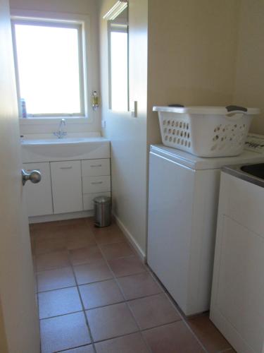uma cozinha com um lavatório e uma máquina de lavar roupa em Gladstone Cottage em Twizel
