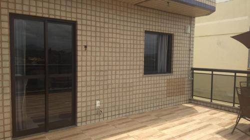a brick wall with a glass door on a patio at Cobertura Aconchegante Itaúna in Saquarema