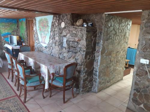 einen Tisch und Stühle in einem Zimmer mit einer Steinmauer in der Unterkunft Cabana Virful Muntelui in Câmpeni