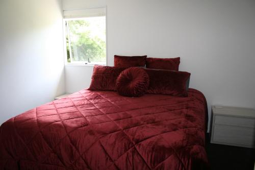 um quarto com uma cama com um edredão vermelho e uma janela em Bridgehaven Guesthouse em Okoroire