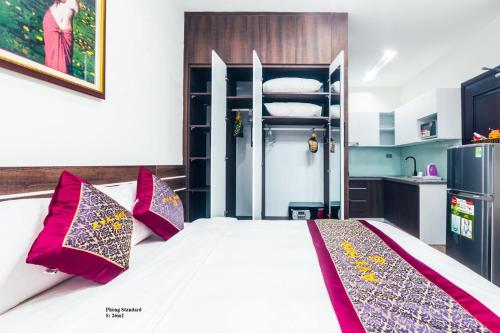 a bedroom with a bed with pillows and a kitchen at AVA Hotel & Apartment in Danang