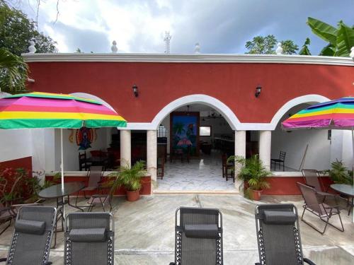 a red building with tables and chairs and umbrellas at Hotel Casona Margot in Valladolid