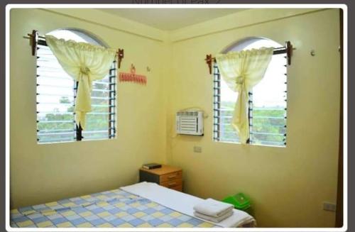 a bedroom with a bed and two windows at Necy's Homestay in Kāman
