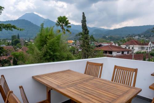 a wooden table and chairs on a balcony with mountains at Three Eight Front One Boutique Batu Malang in Batu