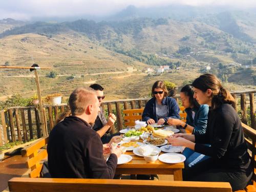 een groep mensen die aan een tafel zitten en eten bij Hoa Chanh Bungalow in Sa Pa