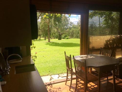 a table and chairs in a kitchen with a view of a yard at The Coach House on River and Park in Mudgee