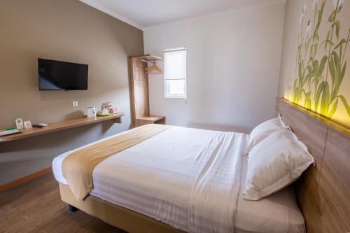 a bedroom with a bed and a tv on the wall at Three Eight Front One Boutique Batu Malang in Batu