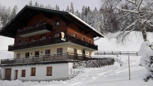 a building with a balcony in the snow at Hallmooshof in Filzmoos
