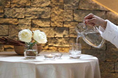 a person pouring water into a glass on a table at Palace Hotel Wellness & Beauty in Bormio