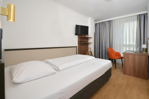 una camera con letto, scrivania e sedia di Hotel Aurbacher Hof GmbH a Monaco