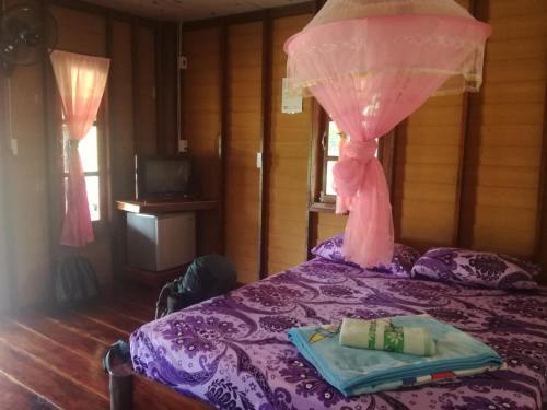 a bedroom with a purple bed with a pink curtain at Mr Bao Homestay & Bungalows in Ko Yao Noi