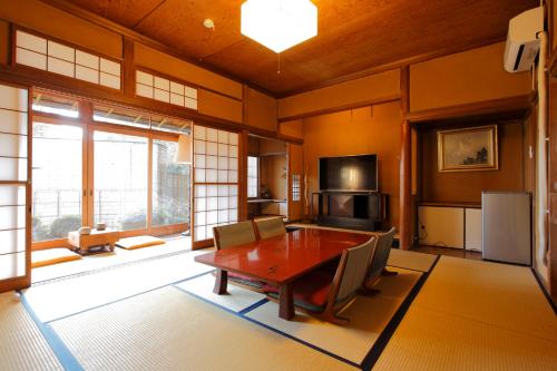 comedor con mesa, sillas y TV en atami onsen guesthouse nagomi en Atami