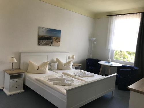 a bedroom with a white bed and a window at Pension Villa Frohsinn Sellin auf Rügen in Ostseebad Sellin