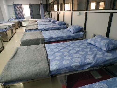 a row of beds in a room at Shiv Sai Dormitory in Vadodara