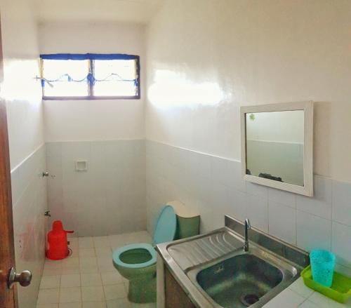 a bathroom with a sink and a toilet and a mirror at WHITE BEACH GUEST HOUSE in Puerto Galera