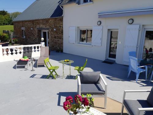 a patio with chairs and a table and a building at Les Suites de Véronique, chez Véronique Olive in Saint-Pair-sur-Mer