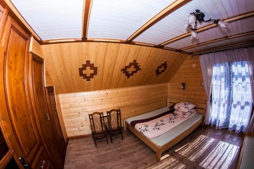 a small bedroom with a bed in a wooden room at Chatka Pod Laskiem - Domki w górach in Soblówka