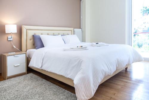 a bedroom with a large white bed with white sheets at TONI'S Apartment near Seaside and Marina Flisvos in Athens