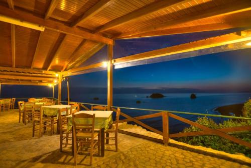 a patio with tables and chairs and a view of the ocean at Christinas lofts in Ágios Matthaíos