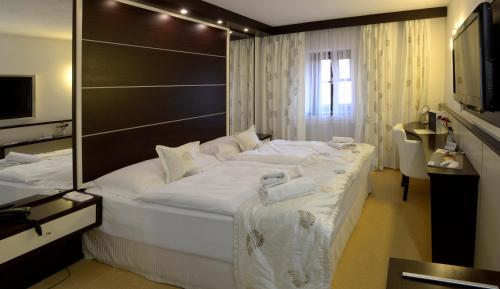 a large white bed in a room with a mirror at Hotel Grand in Český Krumlov