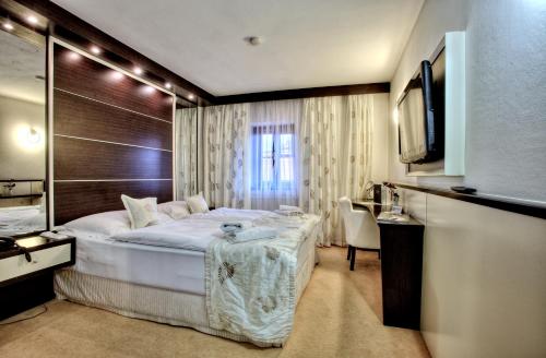 a hotel room with a large bed and a television at Hotel Grand in Český Krumlov