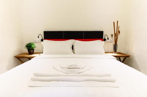 a white bed with two white towels on it at Kuree Hut in Semporna