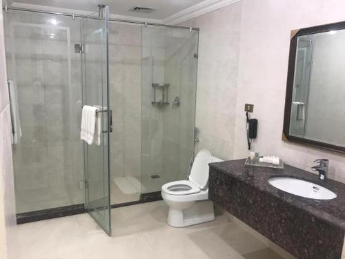 a bathroom with a shower and a toilet and a sink at Etihad Club by Faletti's Hotel in Rahimyar Khan