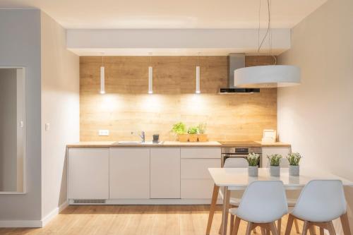 a kitchen with white cabinets and a table and chairs at Kamienica Parkowa in Dąbki