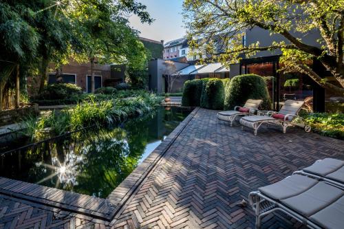 a patio with chairs and a pond in a yard at Cabosse, Boutique Palace & Spa in Antwerp