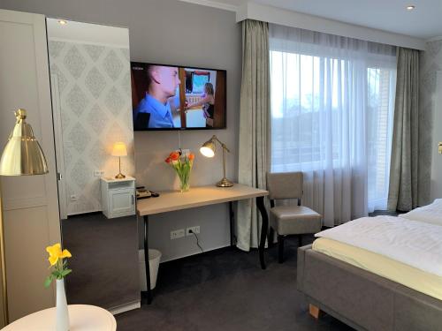 a bedroom with a bed and a desk with a tv on the wall at Hotel-Restaurant Fuchs in Handeloh