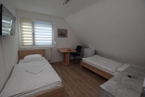 a room with two beds and a desk and a window at AB Möhringen Messe Zimmer in Stuttgart