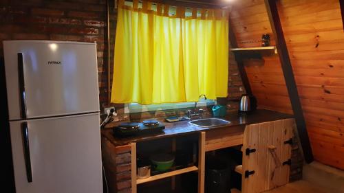 a kitchen with a white refrigerator and a sink at Cabañas "Los Elementos", San Carlos, Salta, in San Carlos