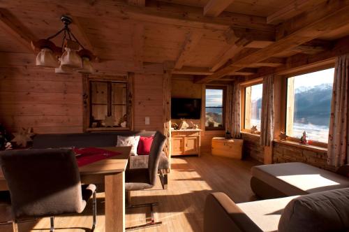 a living room with a table and chairs and windows at Appartements Wallner in Uttendorf