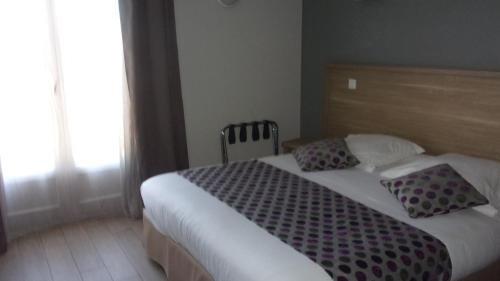 a bedroom with a bed with two pillows on it at Atoll Hotel restaurant in Fréjus