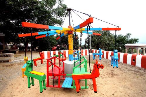 a playground with colorful play equipment in the sand at My Village - Eco Rural Resort in Coimbatore