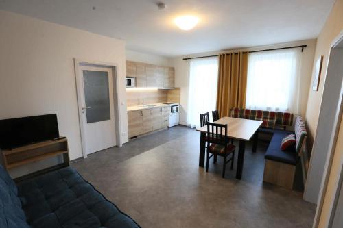 a living room with a couch and a table and a kitchen at Apartmány AURA in Boží Dar