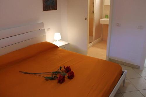 Una cama naranja con flores en un dormitorio en Mono Eraclito, en Marina di Pescoluse