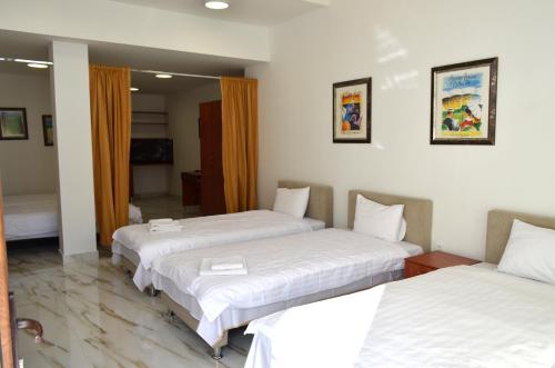 Habitación de hotel con 3 camas con sábanas blancas en Tomce Sofka Apartments, en Skopje