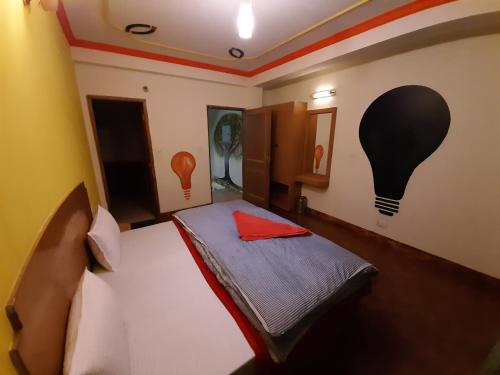 a bedroom with a bed with a light bulb painted on the wall at La Vaca India Manali in Manāli