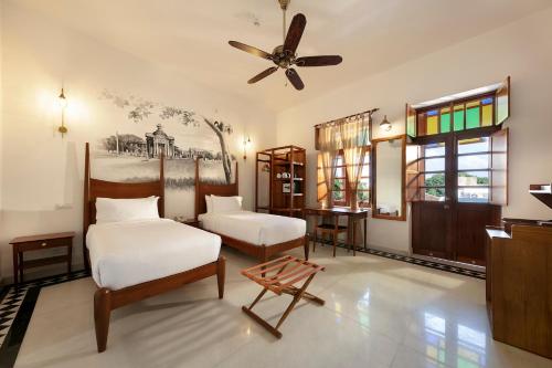 a bedroom with two beds and a ceiling fan at Grand Hotel D'Europe in Puducherry